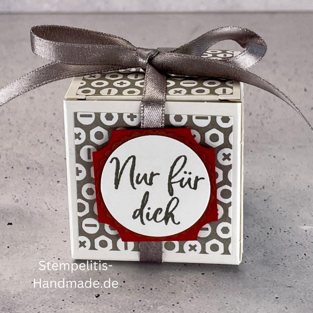 handdekorierte Geschenkschachtel mit Aufschrift „Nur für dich“, Geschenkschachtel mit grauem Muster und rotem Etikett, kleine Geschenkbox mit Satinband, Vorderansicht der Schachtel „Nur für dich“, offene Geschenkbox mit Inhalt, Detailaufnahme Schriftzug „Nur für dich“, stilvolle Geschenkverpackung mit Band